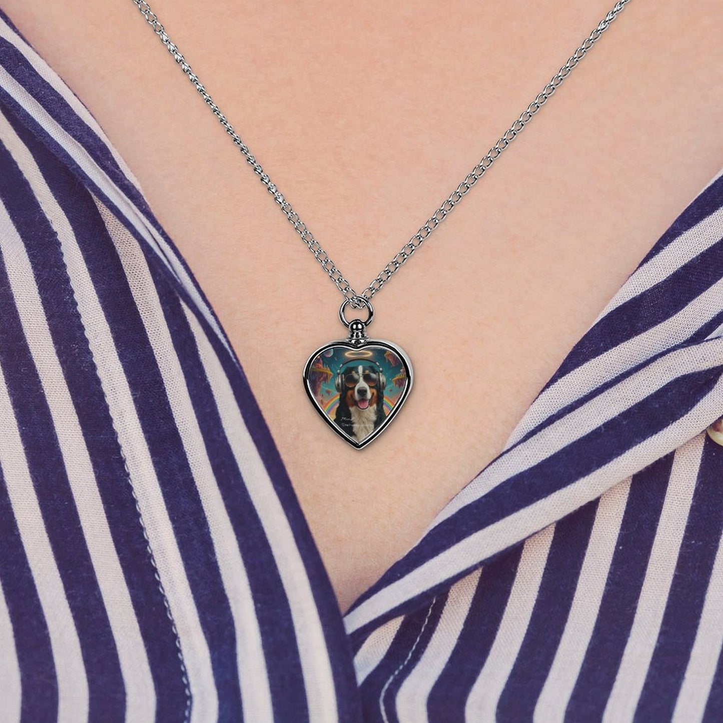 Heart-shaped pendant with a dog's face on a necklace, worn by a person in a striped shirt.