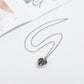 Heart-shaped pendant necklace on a white surface with a magazine in the background